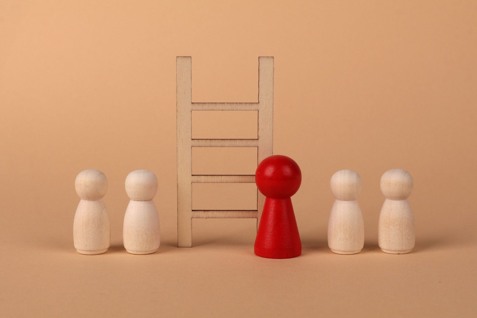 Een rood houten poppetje naast een ladder